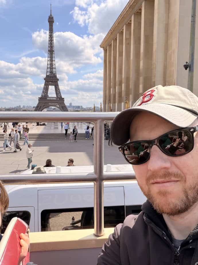 Selfie of a man wearing a beige cap and sunglasses with the Eiffel Tower in the background at Trocadéro, Paris.