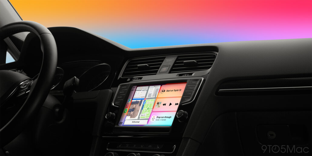 Rivian says AI makes debate over CarPlay completely obsolete - Dans Tutorials - Dans Tutorials Car interior dashboard and steering wheel with a large touchscreen infotainment system, colorful sunset sky visible through the windshield.
