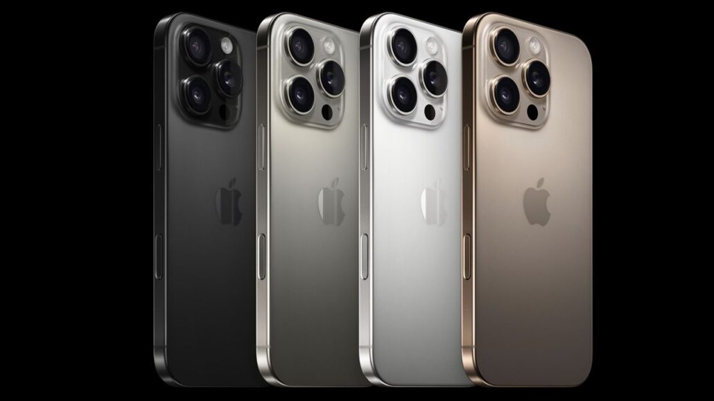Four iPhones with triple-camera backs in black, graphite, silver, and gold, arranged diagonally against a black background.