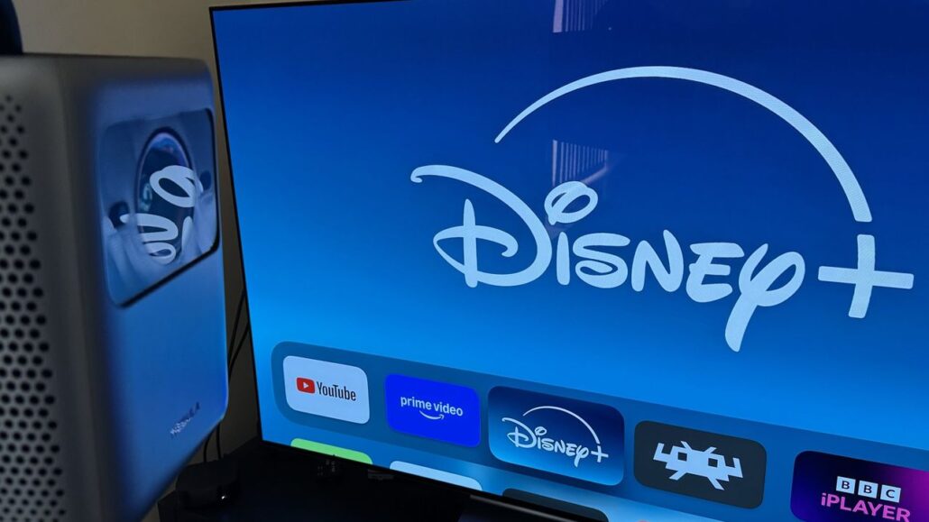 Smart TV home screen showing Disney+ logo with app icons for YouTube and Prime Video