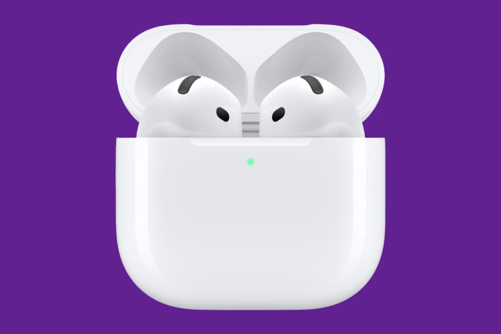 White wireless earbuds in open charging case against a purple background; green status light on case surface visible.