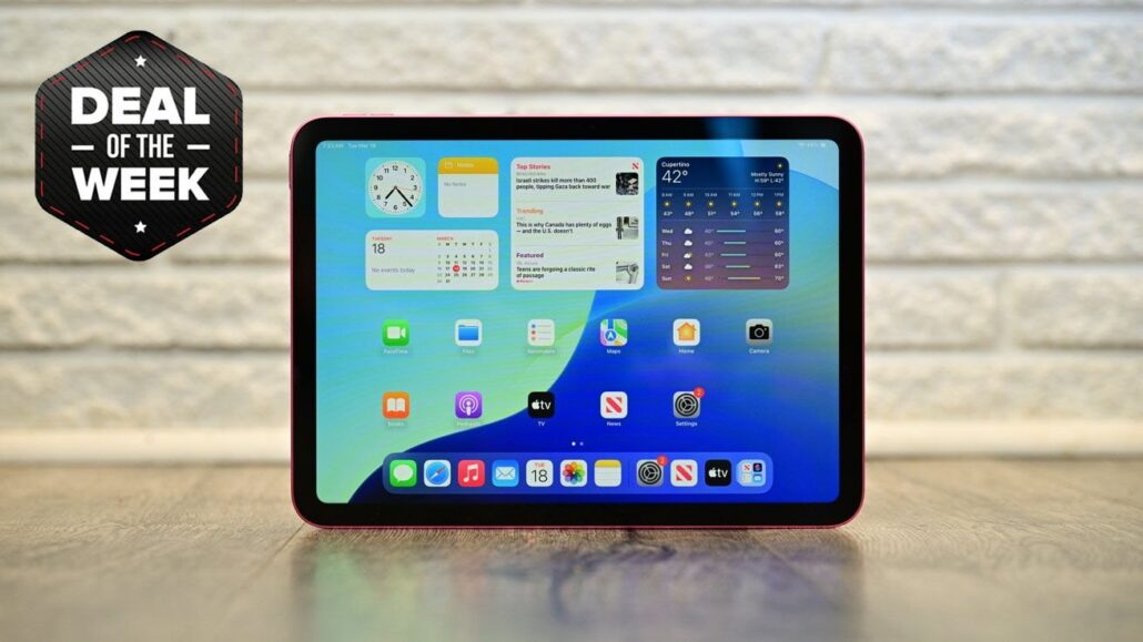 Tablet with a colorful home screen sits on a wooden table; a black 'Deal of the Week' badge is in the upper left corner against a brick wall background.