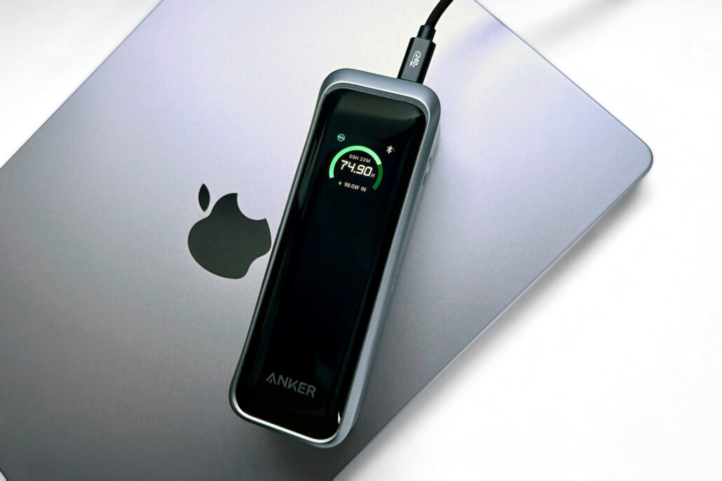 Anker wireless charger placed on a silver MacBook, displaying charging status at 74.90%.