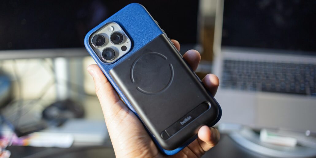 Hands-on Belkins new 25W MagSafe battery packs 10000mAh for your iPhone - Dans Tutorials - Dans Tutorials Hand holding a smartphone with a blue case and a black MagSafe wallet attached, showing the phone's triple-camera module in the corner.