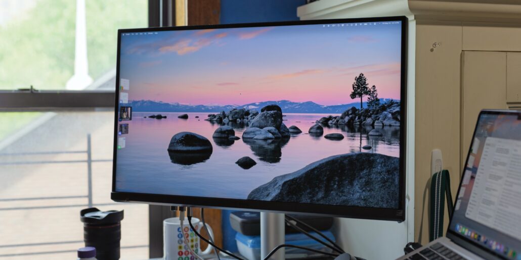 Hands-on BenQs new MA270S is a glossy 27-inch 5K display made for Mac - Dans Tutorials - Dans Tutorials Monitor at a desk displaying a sunset lakescape with rocks in calm water and distant mountains.