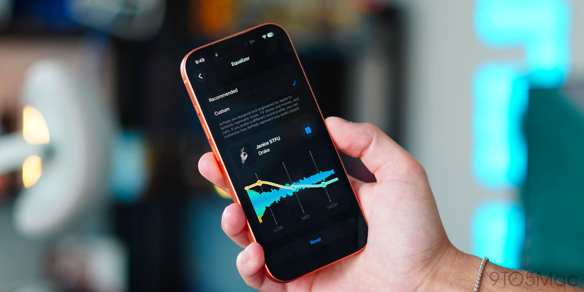 Hand holding a smartphone showing an equalizer screen with waveform and settings in focus.