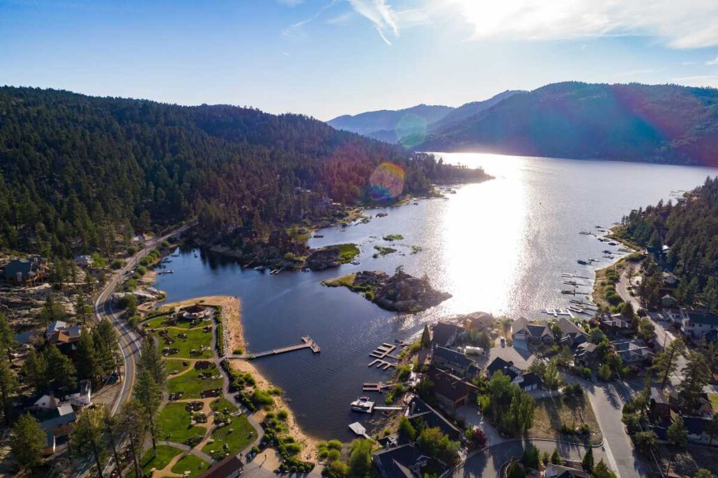 Image slip-up reveals possible name of macOS 27 - Dans Tutorials - Dans Tutorials Aerial view of a lake bounded by forested hills, with a small town, marina, and winding shoreline roads.
