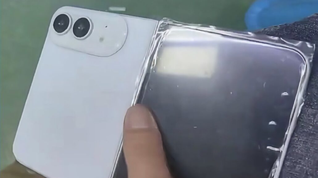 Close-up of a smartphone with dual rear cameras and a clear protective edge being applied by a finger.