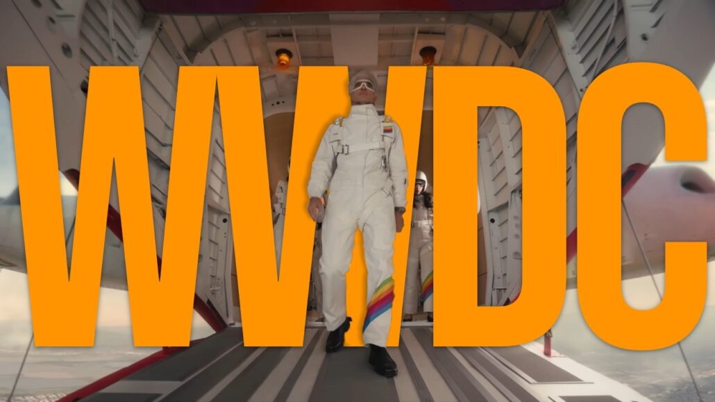 Two astronauts in white suits stand at the open hatch of a spacecraft, with large orange text overlay obscuring the scene.
