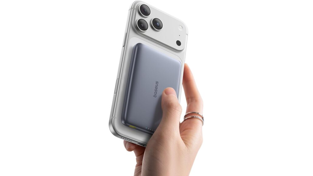 Close-up of a hand attaching a white MagSafe battery pack to the back of a silver iPhone, against a white background.