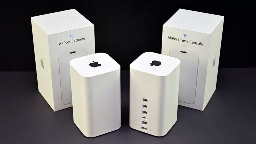 Time Capsule support is dead in macOS 27 but you can keep the hardware alive - Dans Tutorials - Dans Tutorials Two white Apple AirPort wireless routers (Extreme and Time Capsule) with their product boxes in the background on a dark surface.
