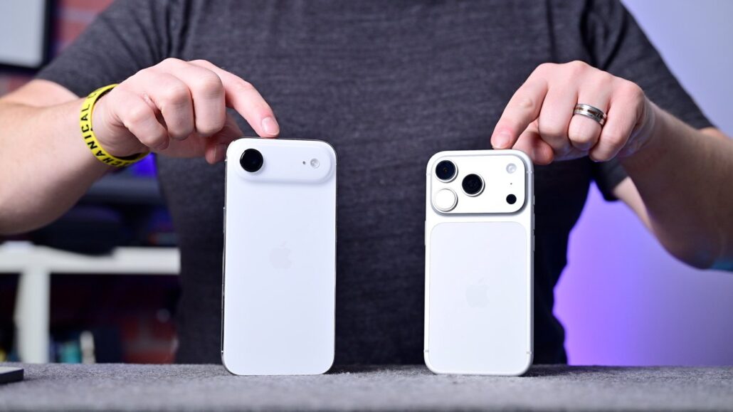 Two white iPhones on a table; left phone has a single rear camera, right phone has multiple cameras